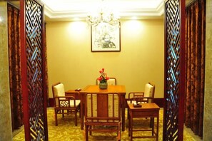 A dining area with a table and chairs, a chandelier, and a framed picture on the wall.