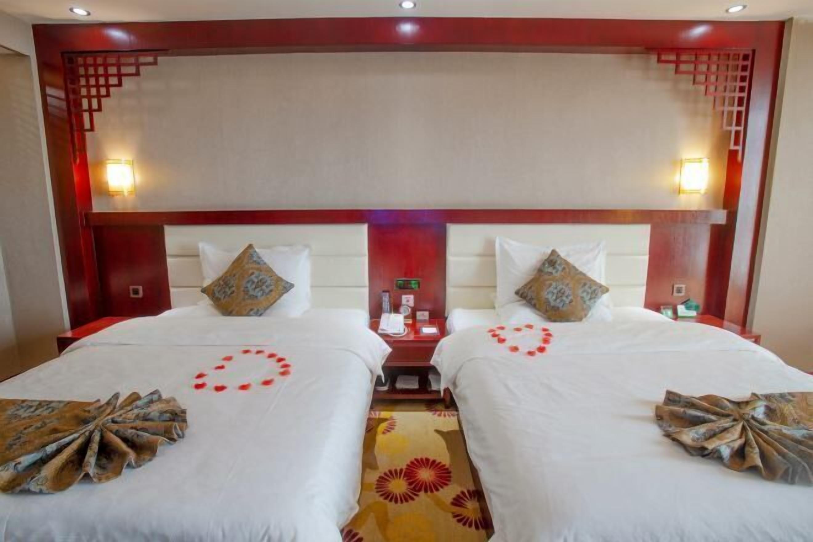 Une chambre d’hôtel avec deux lits, une tête de lit en bois, des lampes de chevet et une petite table placée entre les lits.