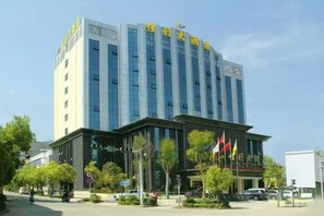 A multi-story building with a modern architectural design, featuring a prominent entrance and several flags.