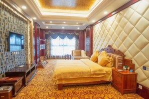 A hotel room with a large bed, a television, a desk, and a window with curtains. - Jia Li Hotel (Dali)