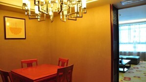 Un comedor con una mesa y sillas rojas, una araña de cristal y una obra enmarcada en la pared.