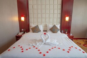 A hotel room with a large bed, two nightstands, a tufted headboard, and wall-mounted lamps. - Jia Li Hotel (Dali)