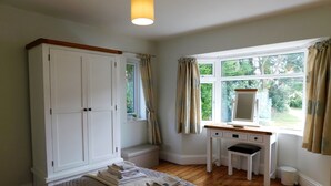 Une chambre à coucher avec un lit, un bureau, une armoire et une fenêtre avec des rideaux.
