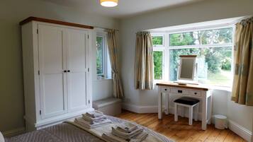A bedroom with a bed, a desk, a wardrobe, and a window with curtains.