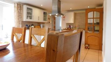 A modern kitchen with wooden chairs, a dining table, and a built-in oven.
