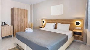 Un dormitorio moderno con una cama grande, cabecera de madera, mesitas de noche con lámparas, un armario y un escritorio pequeño con una tetera.