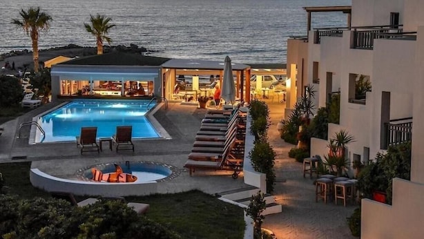 Zona de piscina en un complejo turístico con bar, sillas de descanso y jacuzzi.