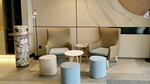 A modern lounge area with two armchairs, a small round table, and three cylindrical stools. - Home Inn Hotel Beijing Miyun Changchenghuandao (Miyun)