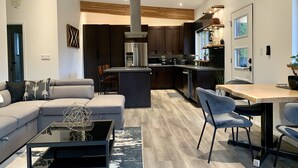 A modern kitchen with dark cabinets, stainless steel appliances, and a central island. - The Treehouse Suite with a roof top jacuzzi hot tub. Private and Quiet. (Bonnington Falls)