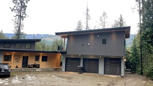 A modern two-story house with a garage, a covered porch, and a view of mountains. - The Treehouse Suite with a roof top jacuzzi hot tub. Private and Quiet. (Bonnington Falls)
