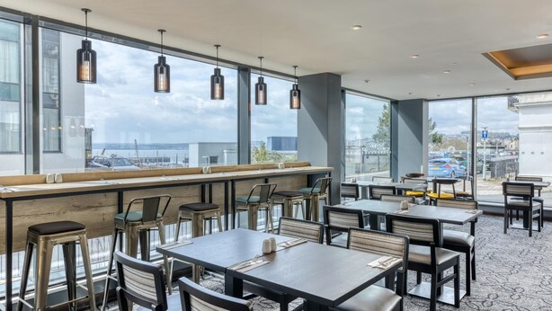 A restaurant with large windows, multiple tables, and chairs. - Premier Inn Torquay Harbour (Torquay)