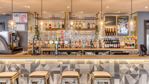 A bar area with a counter, stools, a coffee machine, and a variety of bottles and glasses. - Premier Inn Torquay Harbour (Torquay)