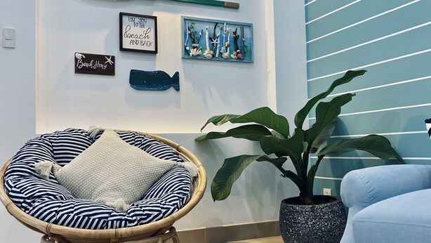 A beach-themed living room with a rattan chair, a potted plant, and a blue sofa.