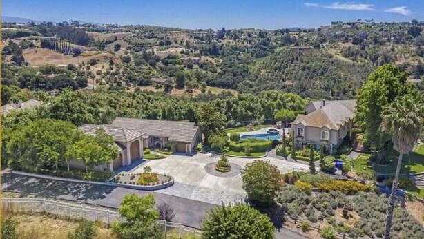 A residential area with a large house featuring a swimming pool, surrounded by lush greenery and hills in the background. - Serene Guest House on Avocado Grove and Vineyard (Fallbrook)