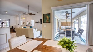 Un vaste espace de vie comprenant une table à manger, un canapé et un balcon aménagé avec des sièges d’extérieur.