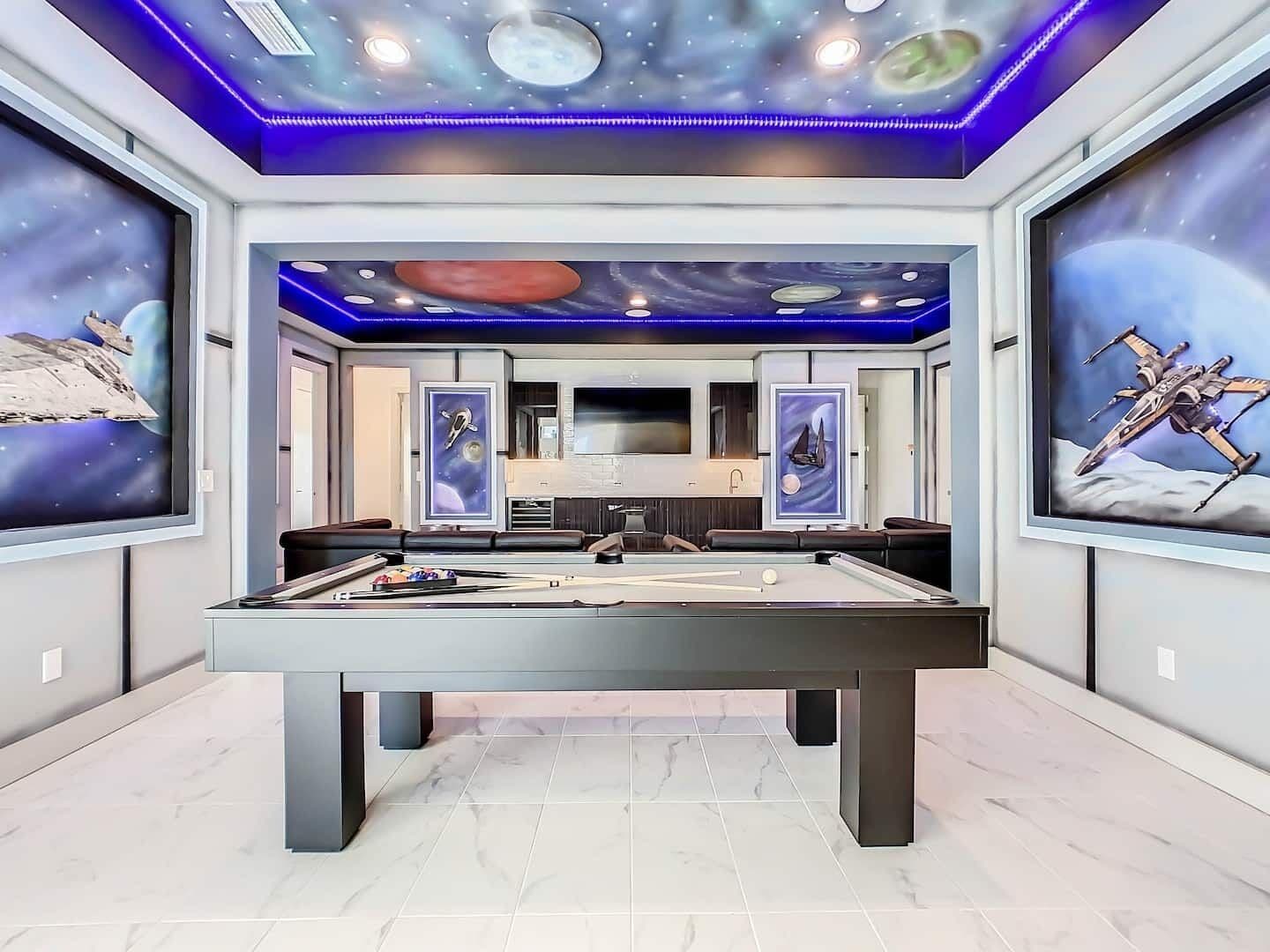 A pool table in a room with space-themed wall art and a modern design.