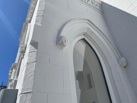 A white building with a large arched window and a stone gargoyle.