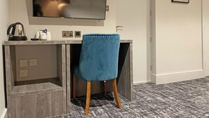 Een moderne kamer met een flatscreen televisie aan de muur, een bureau met stoel, en een kunstwerk in een lijst.