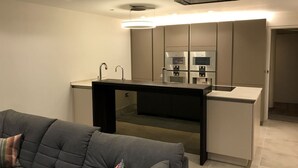 Een compacte keuken met moderne apparatuur, een inbouw eiland en een grijze bank op de voorgrond.