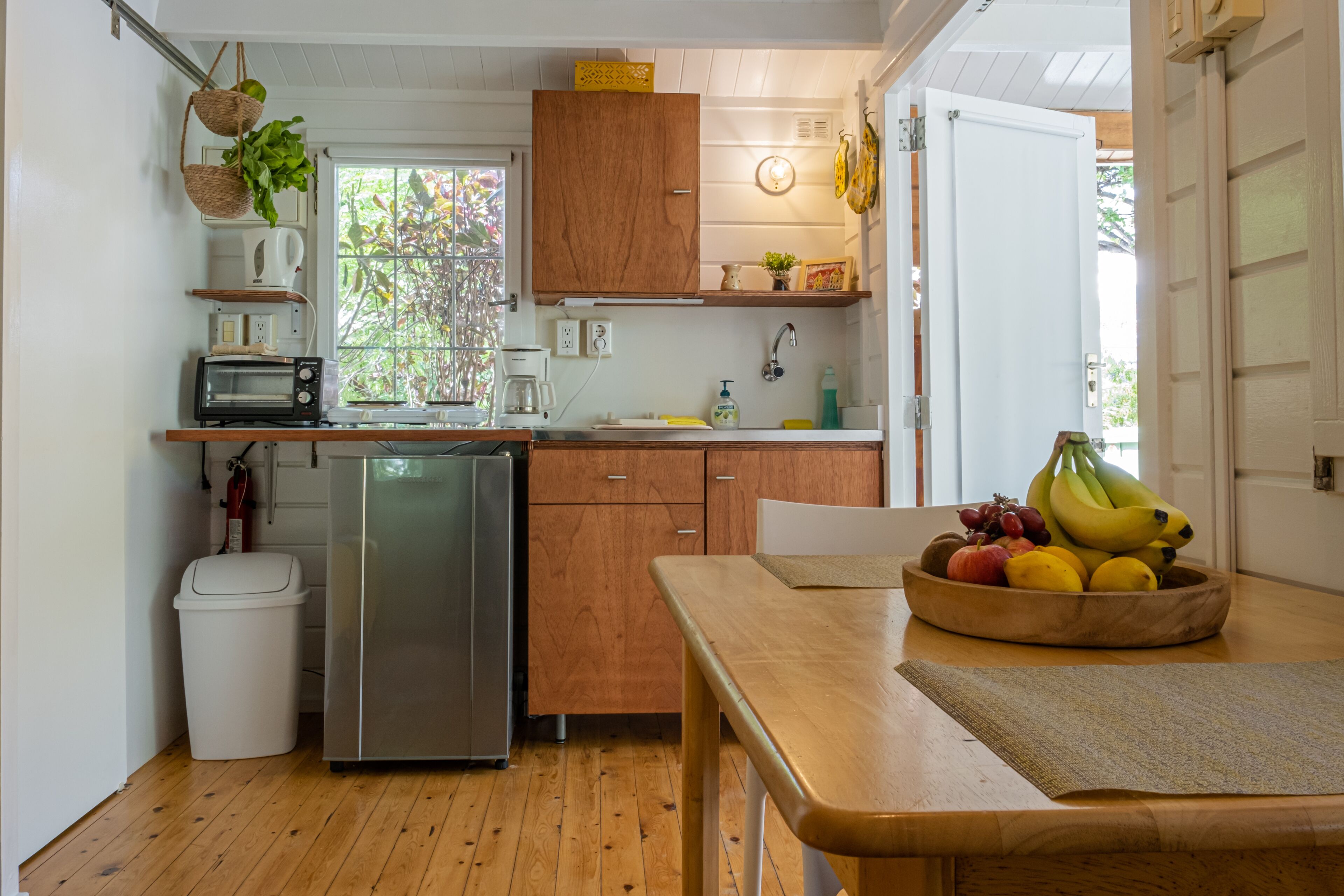 A compact kitchen with wooden cabinets, a built-in oven, a sink, and a window.