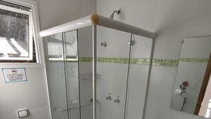 A modern bathroom with a glass-enclosed shower, a marble sink, and a toilet. - Pousada Primavera Campos do Jordão (Campos do Jordão)