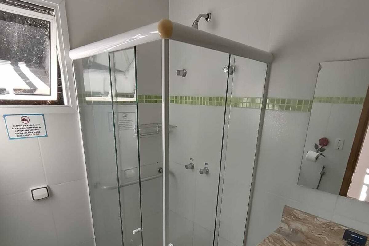 A modern bathroom with a glass-enclosed shower, a marble sink, and a toilet.