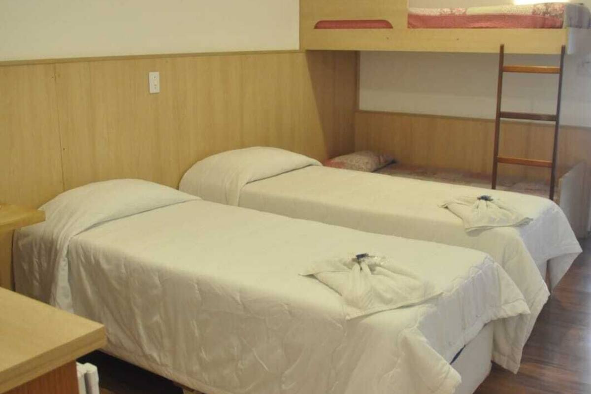 A dormitory room with bunk beds and a ladder.