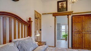 Una camera da letto con testiera in legno, un letto con biancheria da letto a fiori, una lampada da comodino e un armadio in legno.