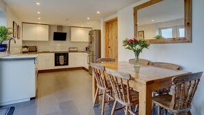 Una cucina moderna con mobili bianchi, un tavolo da pranzo in legno e un grande specchio.