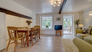 Un vaste espace de vie comprenant une table et des chaises en bois pour les repas, un téléviseur et un canapé.