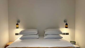A bed with white linens and two wall-mounted lamps on either side.