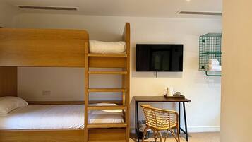 A bunk bed with a desk and chair, a television, and a green wire basket on the wall.