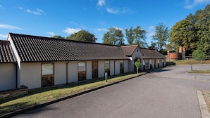 Een rij gelijkvloerse gebouwen met een consistente architectuur, voorzien van pannendaken en een centrale binnenplaats.