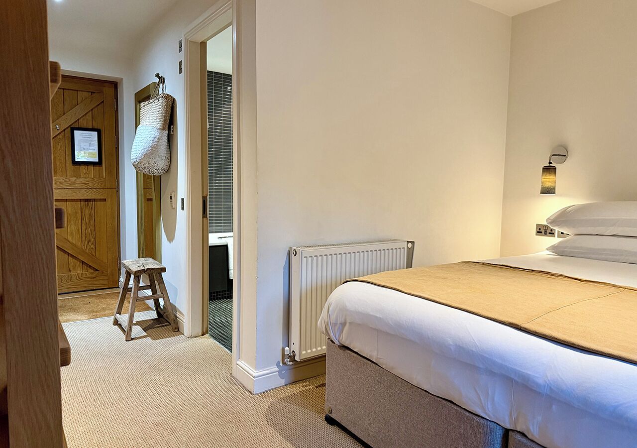 A bedroom with a bed, a radiator, a wooden door, and a small stool.