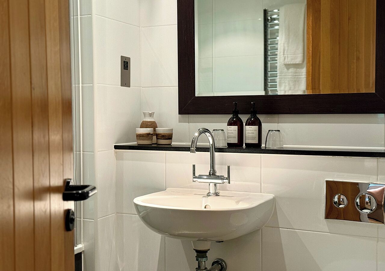 A bathroom with a white sink, a mirror above it, and a wooden door.