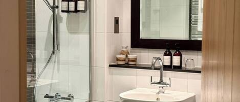 A modern bathroom with a glass-enclosed shower, a white sink, and a mirror above the sink.