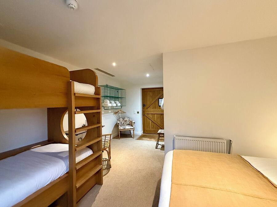 A bunk bed room with a wooden ladder, a chair, and a radiator.