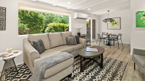 A modern living room with a sofa, coffee table, and dining area. - DreamCatcher-N Walk to Shop/Dine/Hike (Sedona)