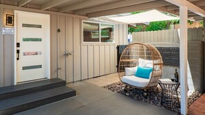 A covered outdoor seating area with a wicker chair, a small table, and a bottle of wine. - DreamCatcher-N Walk to Shop/Dine/Hike (Sedona)