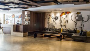 Un vestíbulo moderno con una mesa de recepción, asientos de cuero y arte abstracto en la pared.