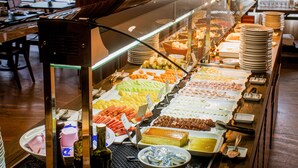 Un bufé con diversos alimentos y una vitrina de vidrio.