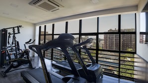 A gym with exercise equipment and large windows offering a city view. - Anna Suites Ipanema (Rio de Janeiro)