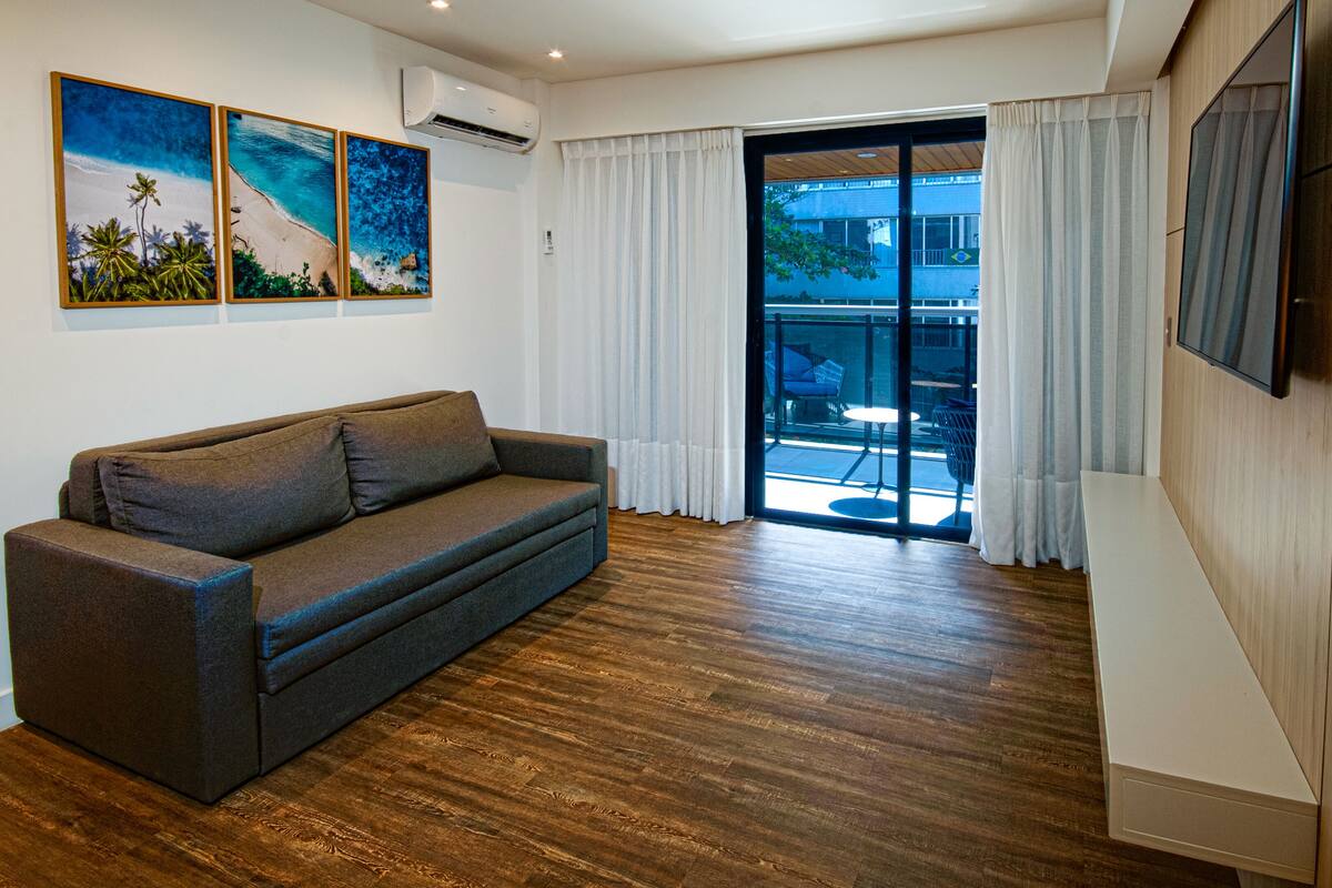 A modern living room with a sofa, a flat-screen TV, and artwork on the wall.