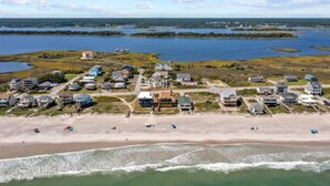 Ovenfra set udsigt over et kystnært boligområde med huse, en strand og tilstødende vandområder.