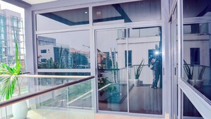 A modern hotel interior with large glass doors, a balcony with a railing, and potted plants. - AMERICA LUXURY EXTENDED STAY (Lagos)