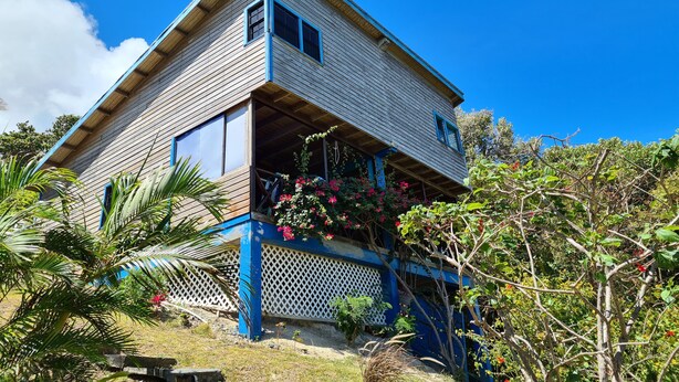 A two-story wooden house with a blue porch and a small balcony. - FISH COTTAGE Almost Paradise (Sauteurs)