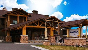 A lodge with a prominent wooden facade, stone pillars, and a clear sky.