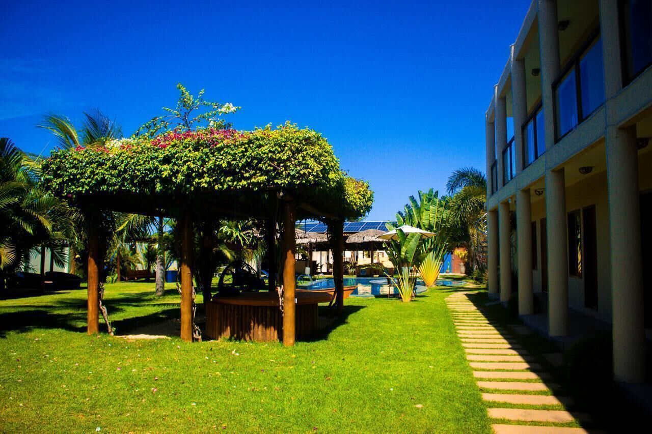 Un jardín bien cuidado con un pabellón, una piscina y un edificio con columnas.