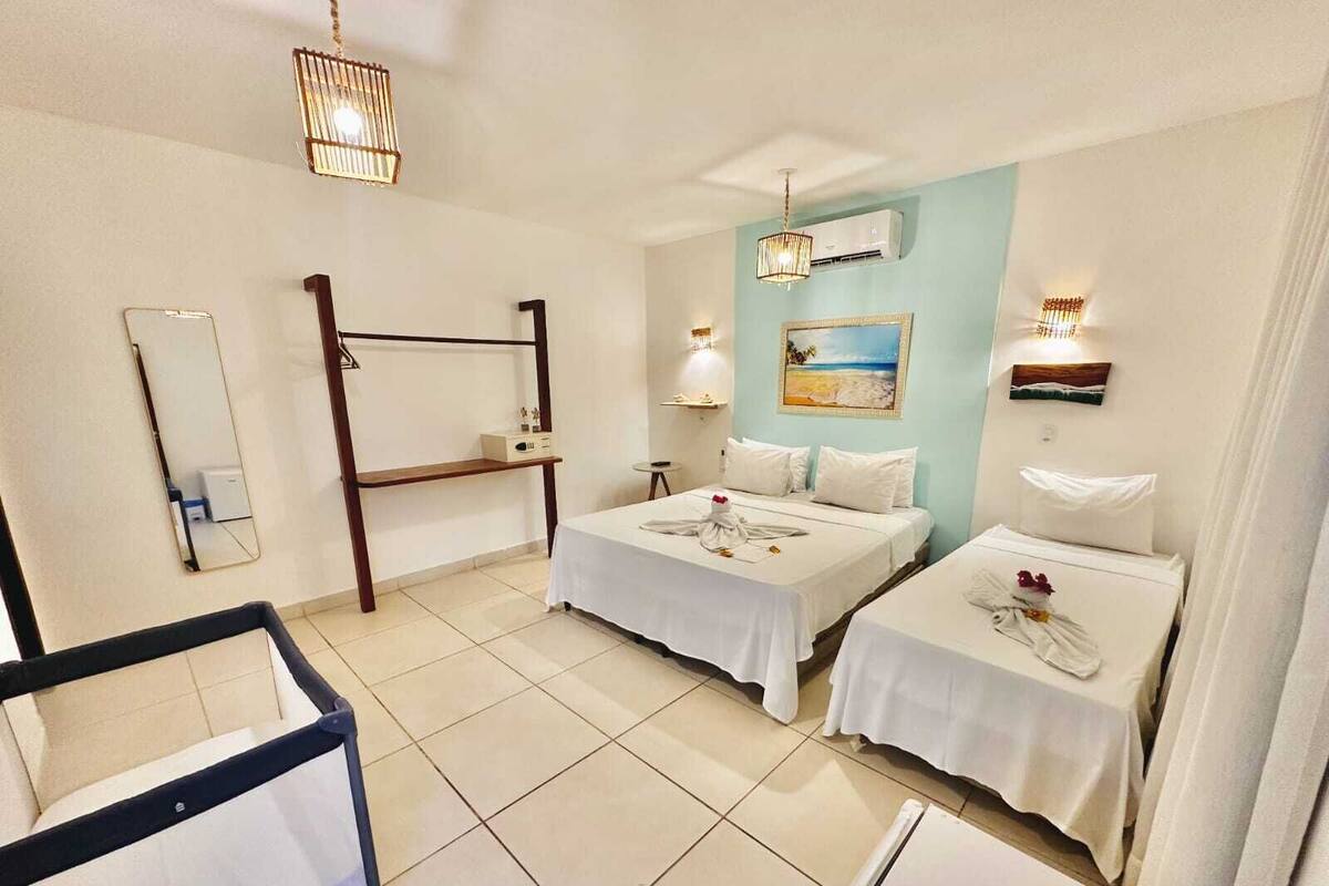 Ein Hotelzimmer mit zwei Betten, einem Etagenbett, einem Nachttisch, einem Spiegel und einem Bild an der Wand.