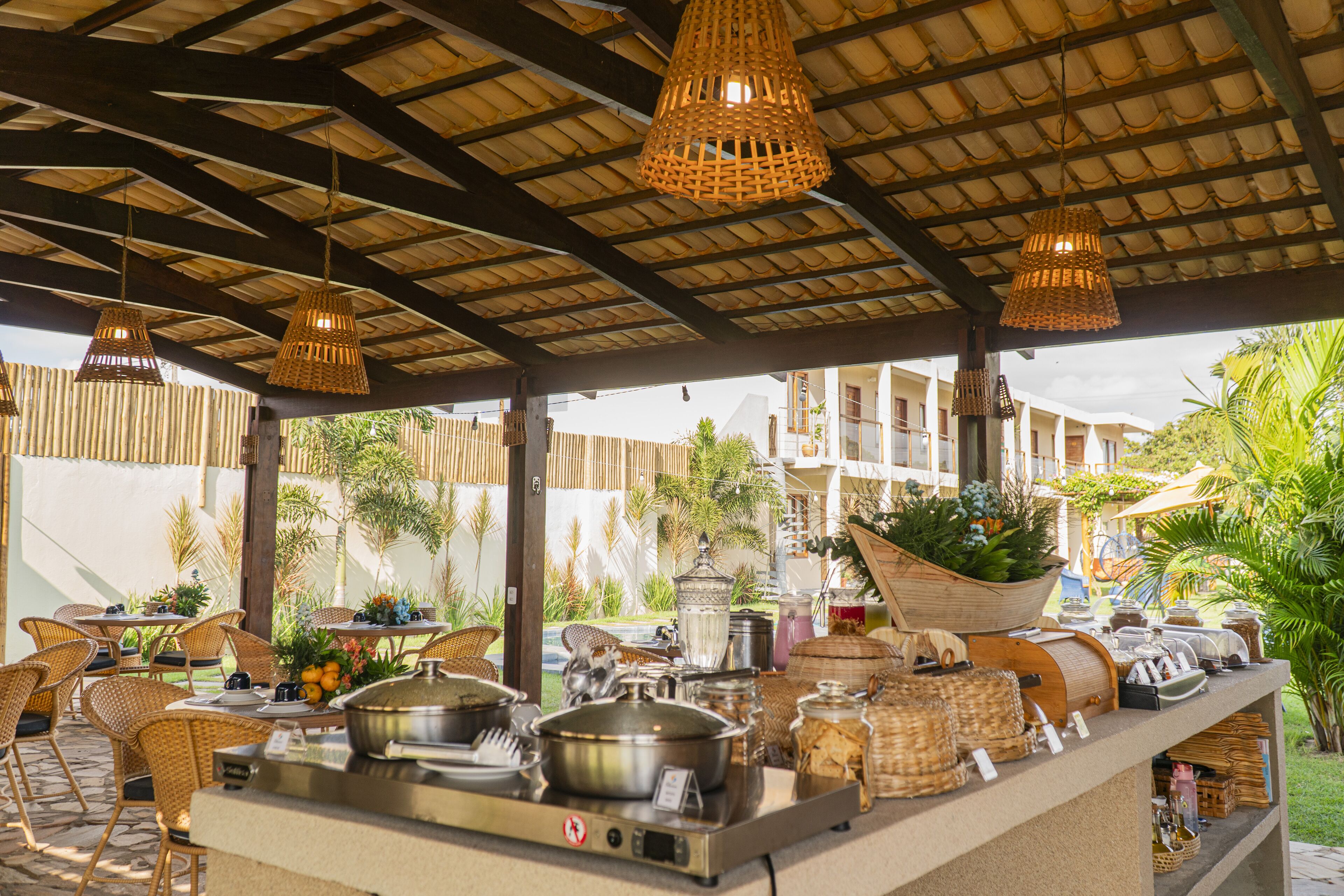 An outdoor dining area with wicker furniture, a buffet setup, and a view of the surrounding greenery.